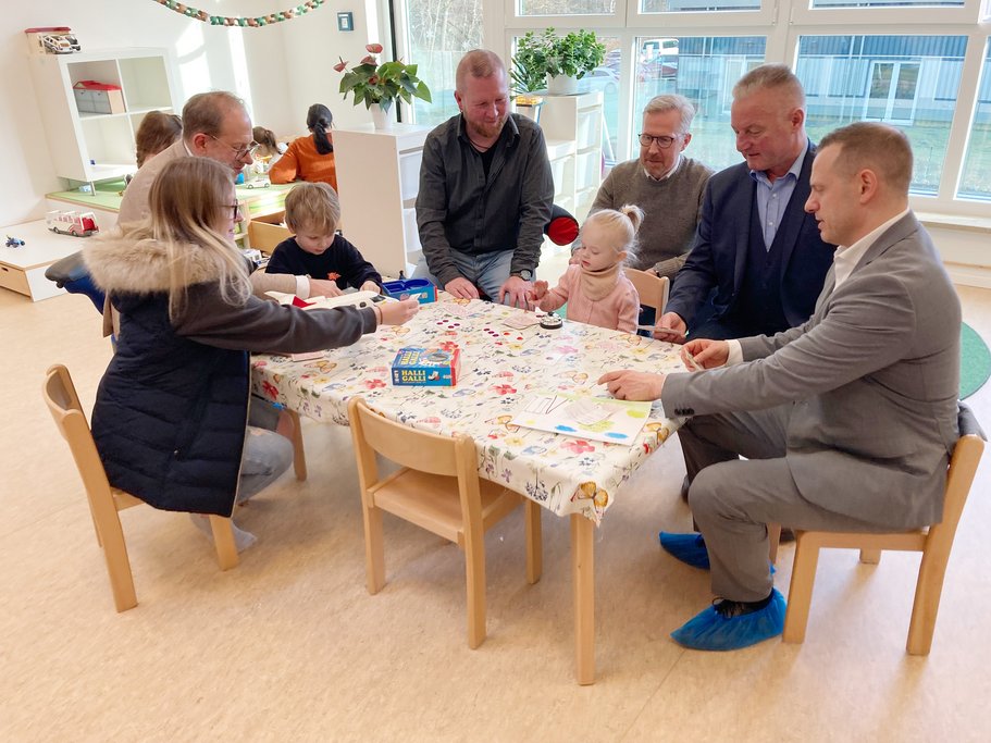 Erwachsene und Kinder sitzen an Kindermöbeln und basteln.