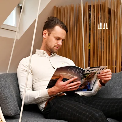 Ein Mann sitzt im Hängesessel im Aufenthaltsraum und liest ein Magazin.