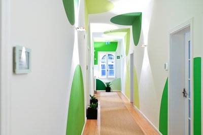 Ein Flur im WOBAU Geschäftsgebäude. An den Türen stehen Pflanzen und an den Wänden und Decke sind unterschiedlich große und grüne Kreise.