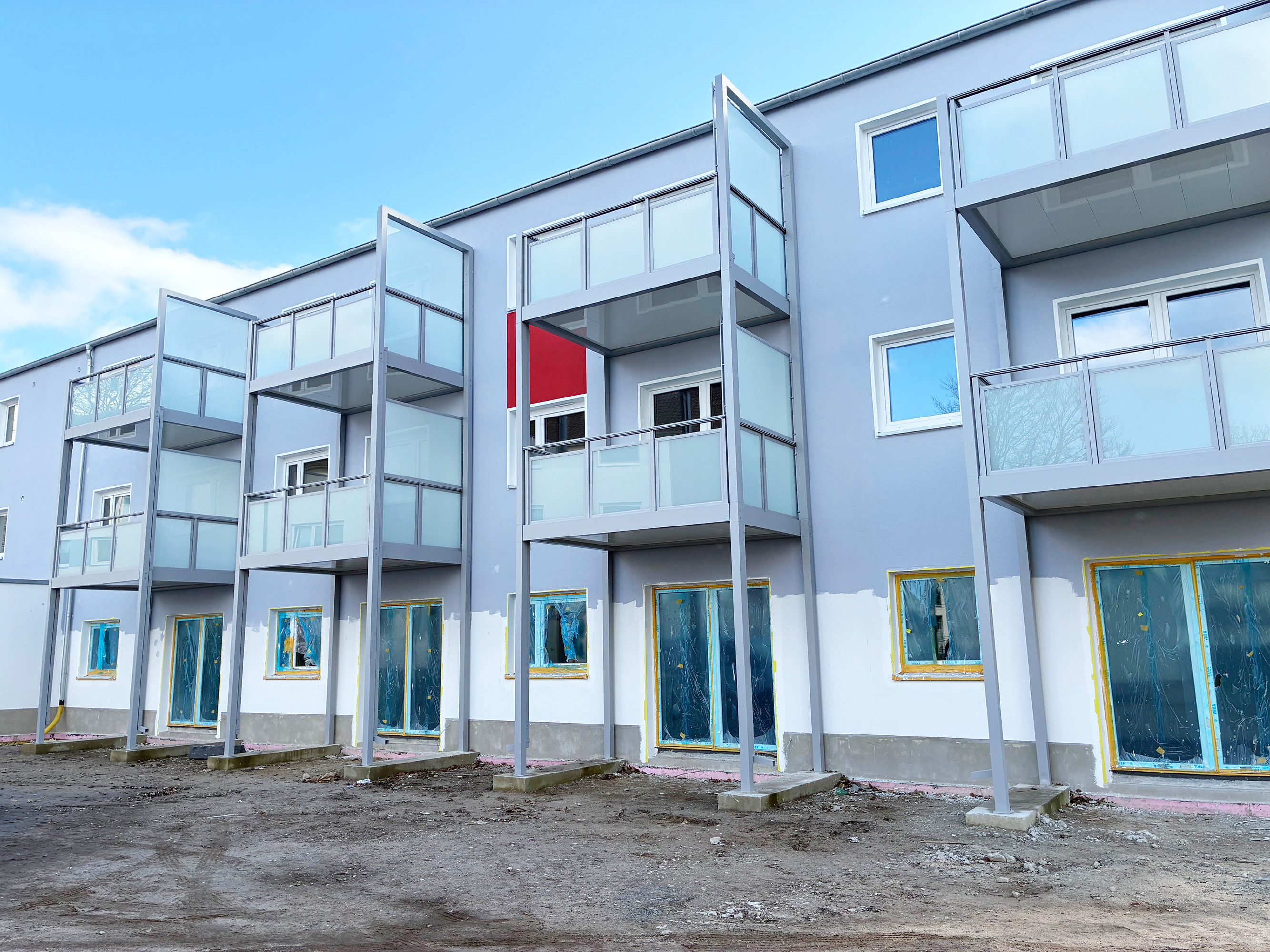 Rückansicht des Neubaugebäudes in der Lötzer Straße kurz vor Fertigstellung. Die Fenster sind abgeklebt, die großen Balkone und Terrassen sind schon vorhanden.